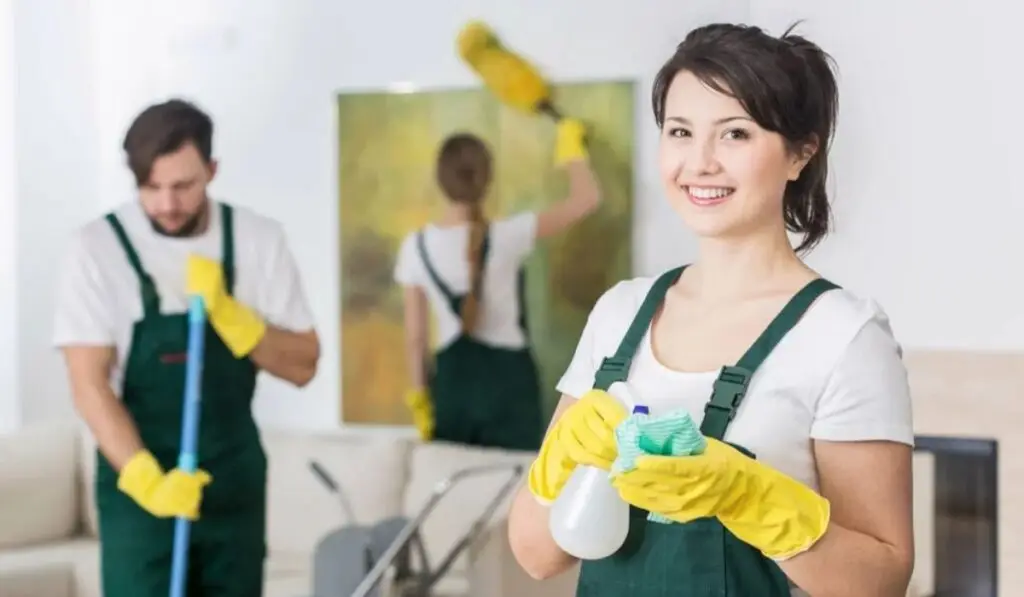 three cleaners cleaning up a room with cleaning supplies