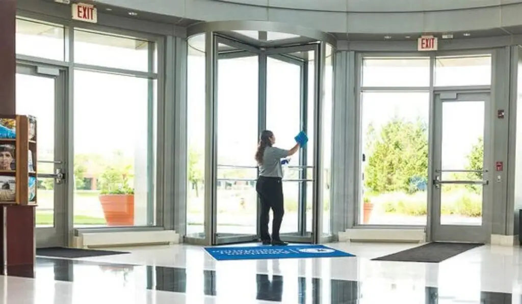 A woman cleaning the glass door in a commercial building