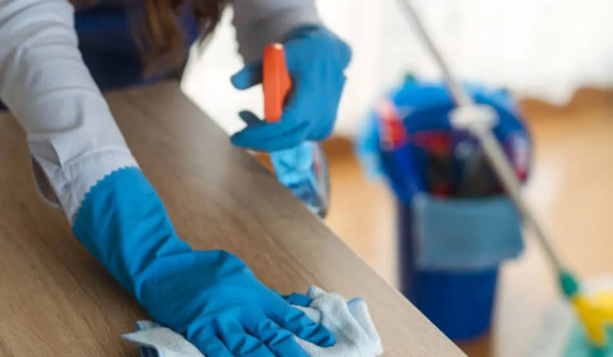 a-woman-wiping-the-table-surface-while-wearing-rubber-gloves