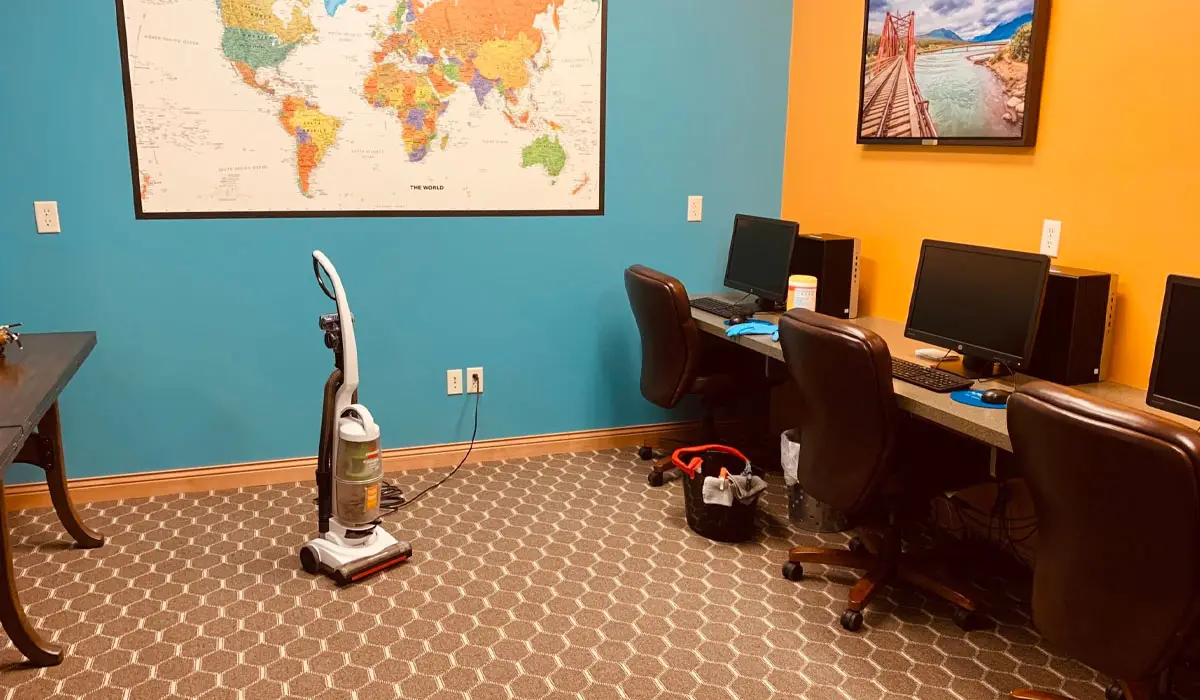 a workspace with office chairs, computers, and a vacuum cleaner