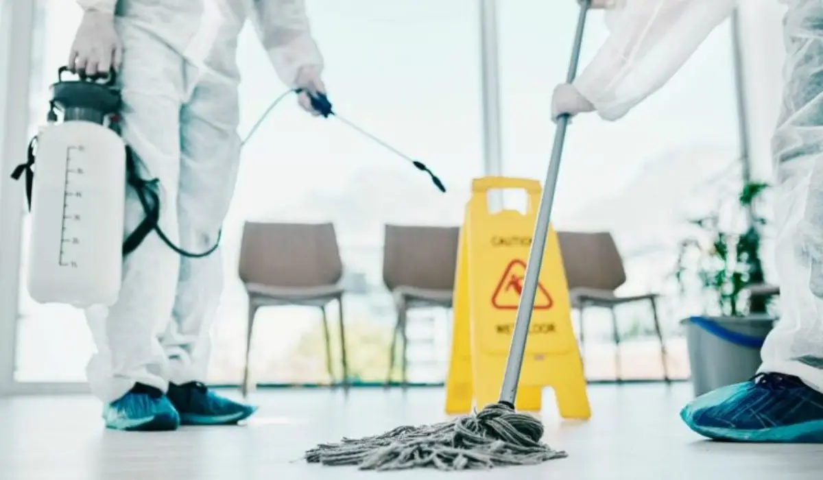 two men wearing PPE and mopping the floor