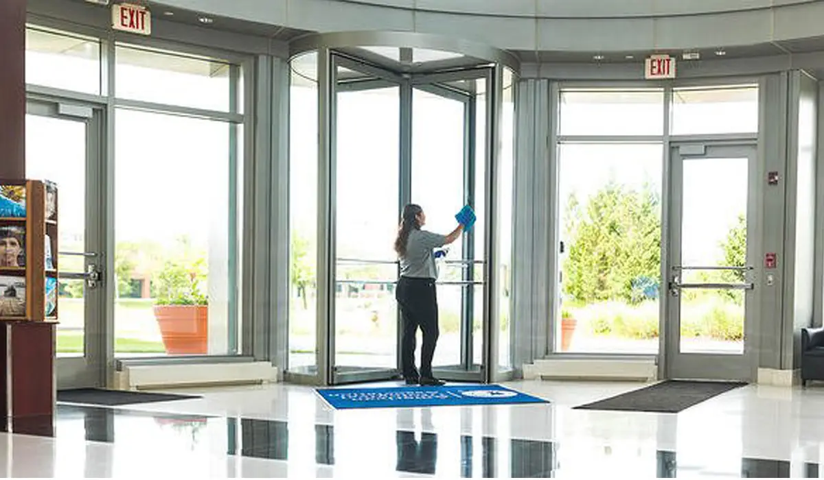 woman wiping the glass doors in the building