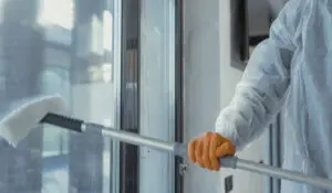 A Man wearing an orange gloves was cleaning the window | Exterior Specialty Cleaning