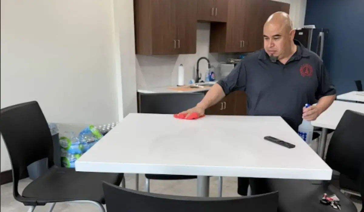 Cleaner disinfecting breakroom table as part of maintaining a professional office environment in Deforest WI.